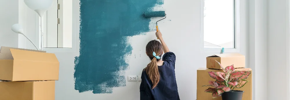 Person streicht Wand mit Farbrolle
